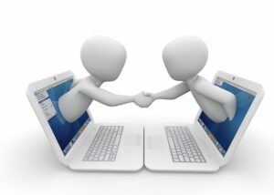 Vertragsabschluss. Zwei Männer geben sich aus einem Monitor heraus die Hand. Bild von Peggy und Marco Lachmann-Anke auf Pixabay